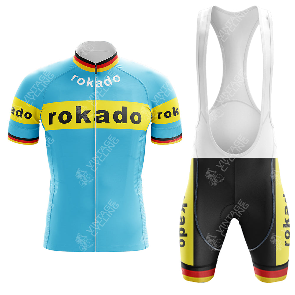 The Boule dOr Sunair Retro Short Sleeve Cycling Set features a blue jersey with yellow bands and rokado text in black. The matching bib shorts are black with yellow accents and the same text. Red and black stripes complete this vintage-inspired look.