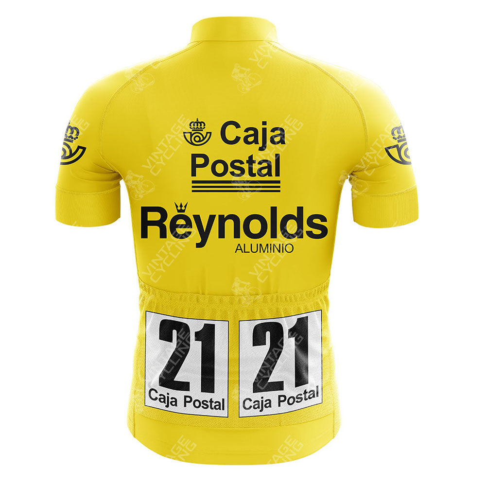 A retro yellow Del Tongo-MG Maglificio Cycling Set jersey with bold black Caja Postal and Reynolds Aluminio logos on the back, plus two race number tags—both marked 21 Caja Postal—pinned to the lower back.