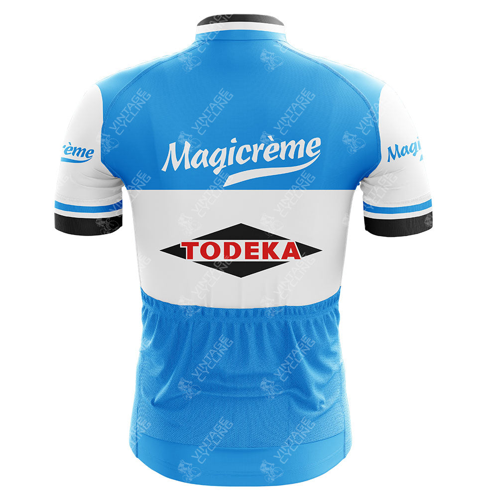 The back view of the Todeka Magicreme Retro Cycling Jersey features a blue and white design. The top displays Magicréme on blue, while the middle is white with a red and black Todeka logo. Made from lightweight polyester, it has blue accents on the sleeves and lower part, plus a secure silicone waist strip.