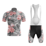 The Floral Grey Pink Cycling Jersey Set includes a grey short-sleeve jersey with pink rose patterns and black bib shorts. The jersey features a full front zipper, and the bib shorts have white straps that add to its retro charm.