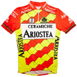 The Ceramiche Ariostea Colnago 1990 Retro Cycling Jersey features a yellow geometric-patterned body with red shoulders. Made of lightweight polyester, it showcases Ariostea, Colnago, and Ceramiche logos, complemented by multicolor stripes on the sleeves and collar for a classic look.