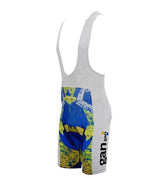 Gan Bib Shorts showcase a vibrant design with blue, yellow, and green abstract patterns and Gan text on the side. They feature a gel pad seat for extra comfort, white straps, and are set against a white background.
