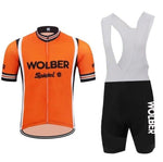 Wolber Spidel Retro Cycling Jersey Set: Orange short-sleeve jersey with a front zipper and WOLBER Spiele text, made from lightweight polyester, paired with black bib shorts featuring white straps and WOLBER on the thigh.