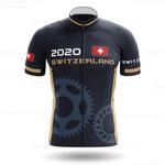 The Swiss Pro Team Cycling Jersey is a lightweight polyester design featuring 2020 and Switzerland text, with Swiss flag logos on the chest and sleeves. It is tailored for performance with gear-like patterns at the bottom in dark gray.