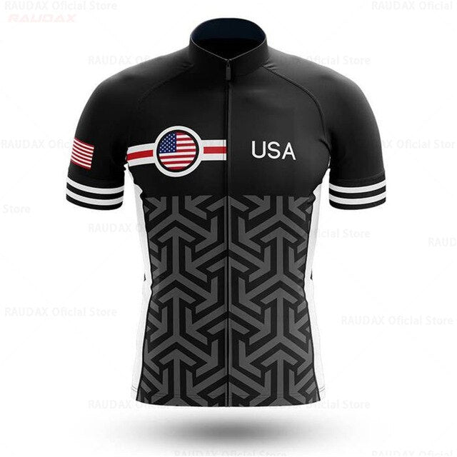 The USA Patterned Cycling Team Jersey features a USA flag patch and USA text on a black and white geometric design. Made of lightweight polyester, it includes striped sleeve accents, reflecting the essence of a USA Pro Team Cycling Jersey.