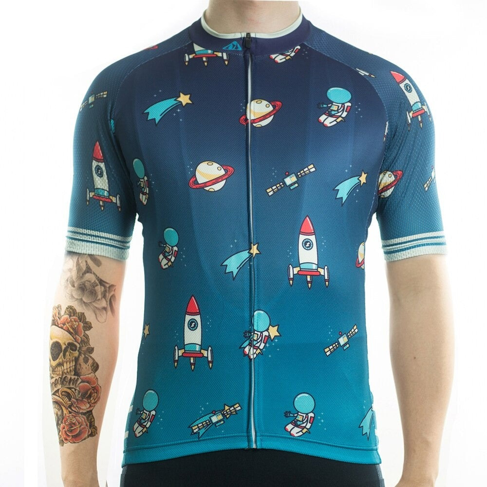 A person wearing the Rockets and Space Cycling Jersey with lightweight polyester fabric, featuring cartoon rockets, astronauts, planets, and satellites. Their tattooed arm displays a skull and floral motif.