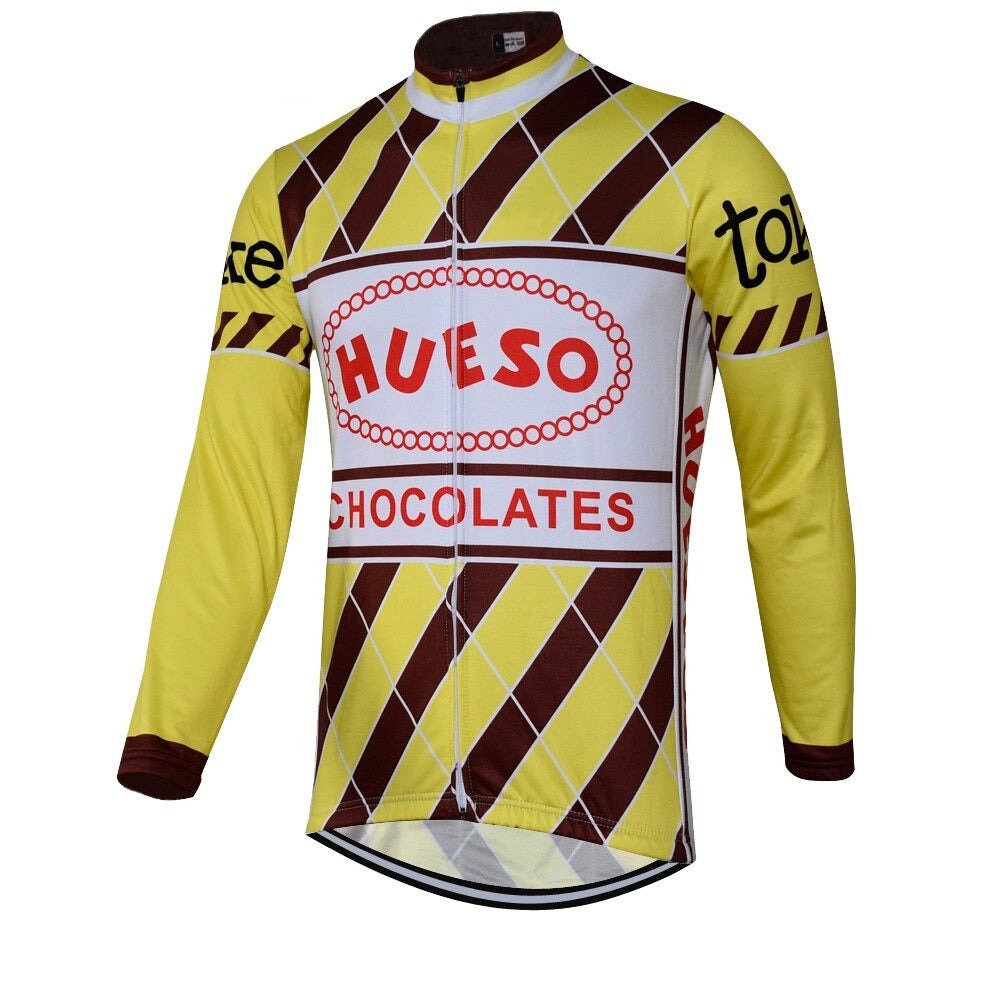 The Hueso Chocolates Retro Cycling Jersey showcases a vintage chocolate wrapper design with prominent Hueso Chocolates branding. Its yellow and brown diamond pattern, complemented by long sleeves with brown diagonal stripes, offers a unique look. A fleece option is available for added warmth.