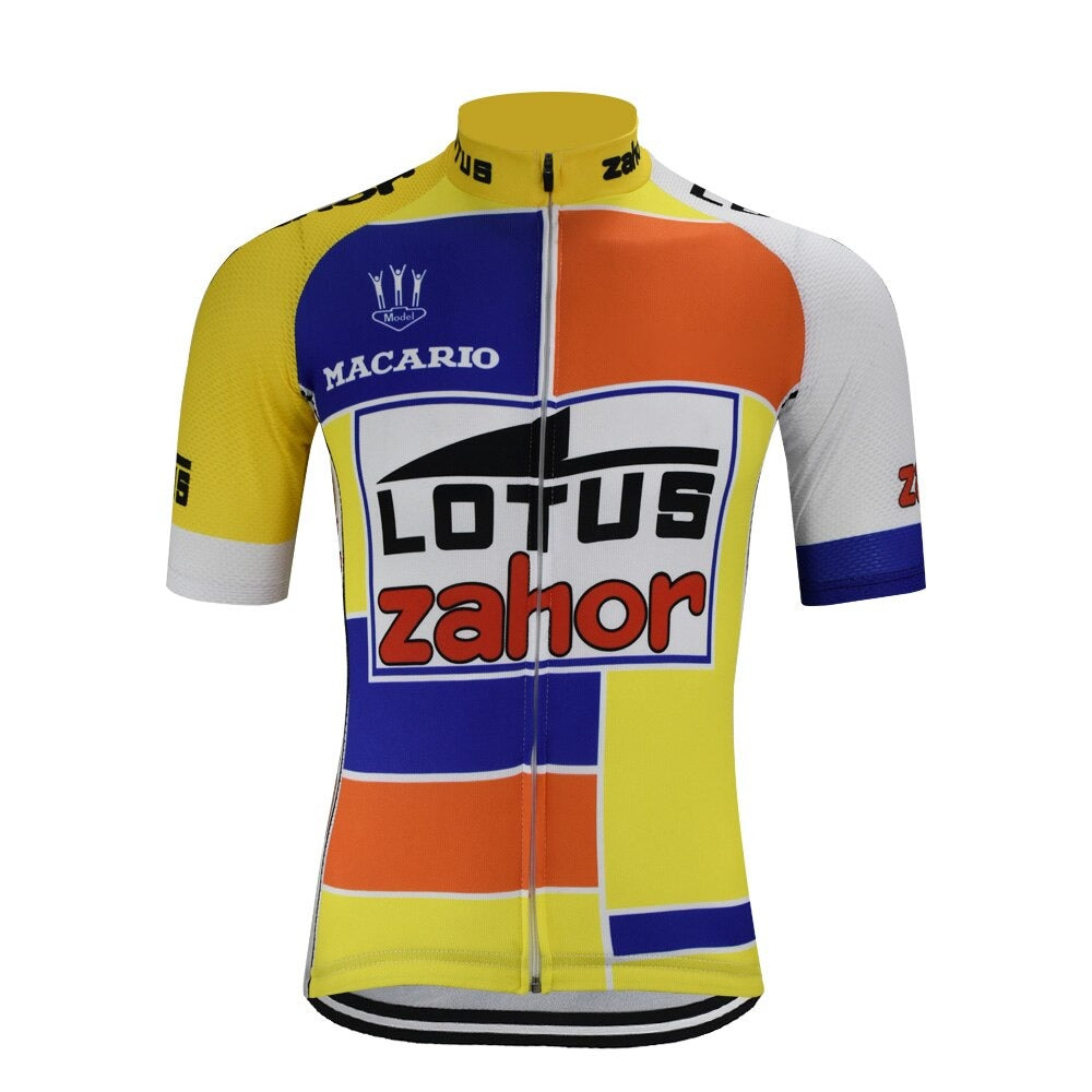 The Lotus Zahor 1989 Retro Cycling Jersey showcases a colorful geometric design with yellow, orange, and white blocks. It features Macario and Lotus Zahor logos, short sleeves, and a front zip to evoke the classic style of the 1989 cycling jersey era.
