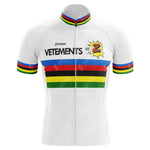 The Tomasso Team Z Vetements Jersey is a white cycling jersey with horizontal stripes in blue, red, black, yellow, and green. It features the Z burst and VETEMENTS logos on the chest and sleeves with a matching collar, perfect for fans of Greg LeMonds iconic Tour de France style.