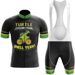 The Wales Men Short Sleeve Cycling Set features a black and green jersey with a cartoon turtle on a bike and "Turtle Cycling Team Shell Yeah!" text; matching bib shorts complete this fun Chicago cycling kit.