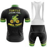 The Wales Men Short Sleeve Cycling Set includes a black and green jersey and bib shorts. The kit features a cartoon turtle on a bike with "Turtle Cycling Team" and "Shell Yeah!" in bold yellow letters on the back.