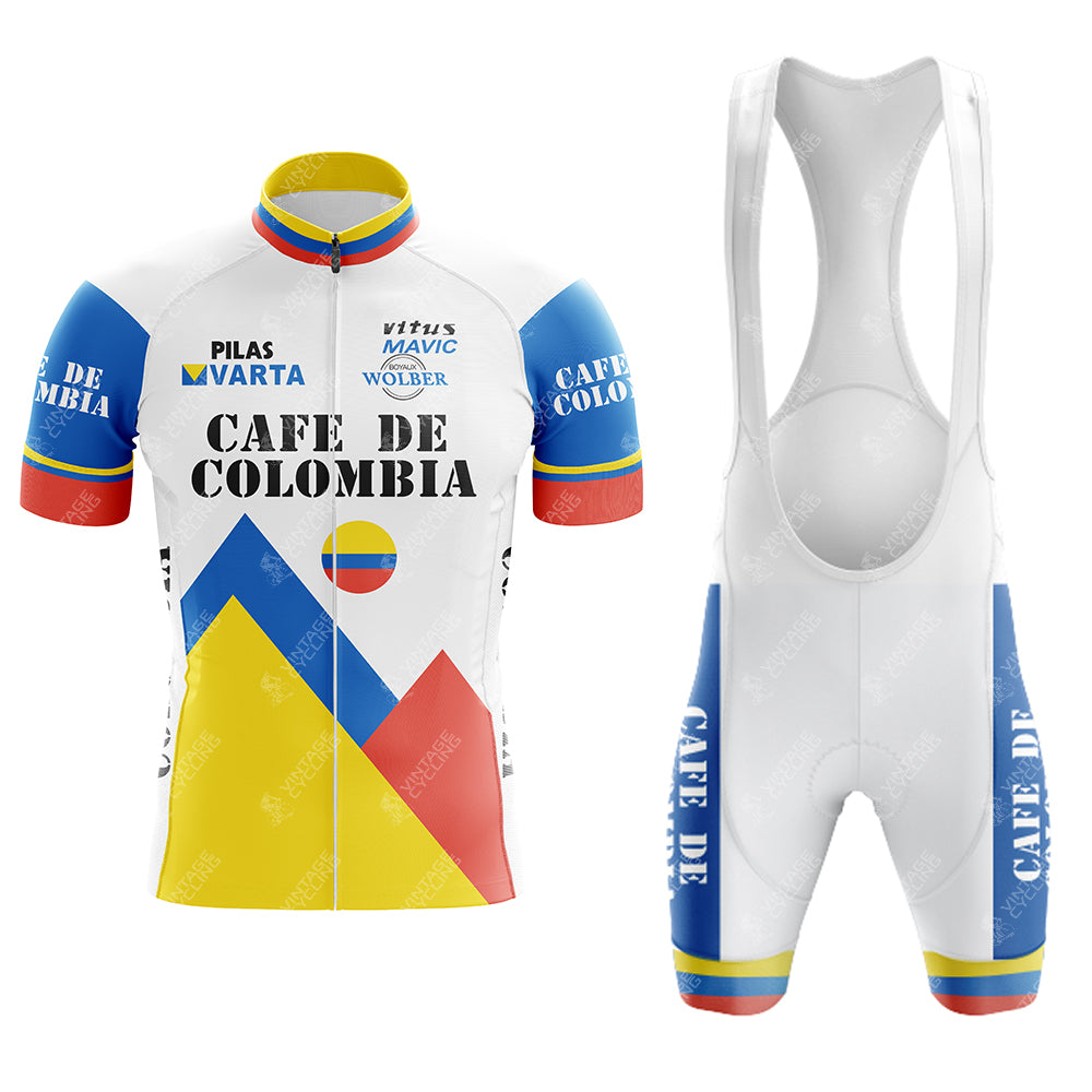 The Cafe D Colombia Retro Short Sleeve Cycling Set includes a white jersey and bib shorts with blue, yellow, and red accents. The jersey showcases Cafe de Colombia text and mountain designs. Both pieces feature logos and patterns, embodying a Colombian theme.