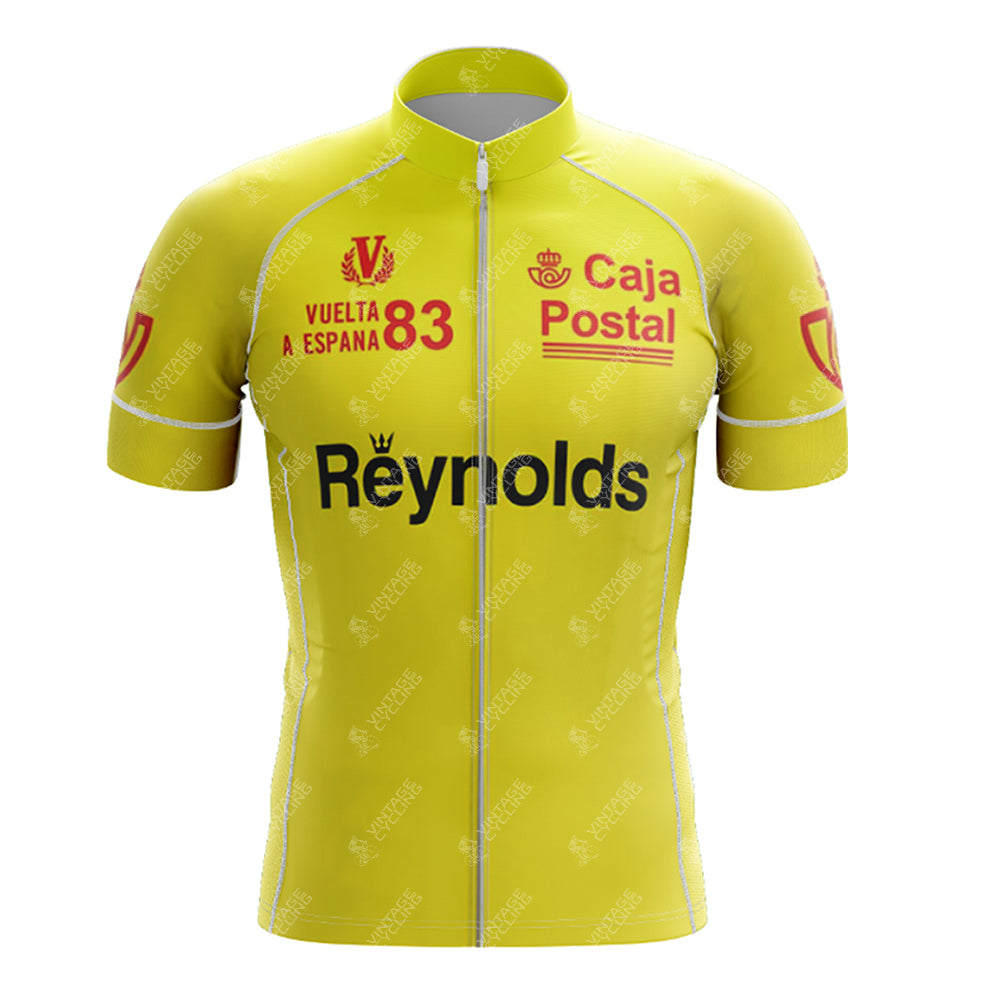 The 1983 yellow Reynolds Retro Short Sleeve Cycling Set features logos and text like Caja Postal and Vuelta a España 83, with a front zipper and red accents, capturing the classic cycling era.
