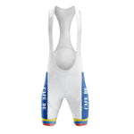 Front view of white cycling bib shorts from the Cafe D Colombia Retro Short Sleeve Cycling Set, featuring blue side panels with CAFE DE text and a yellow/red stripe at the hem. Includes shoulder straps and a padded seat area for optimal comfort.