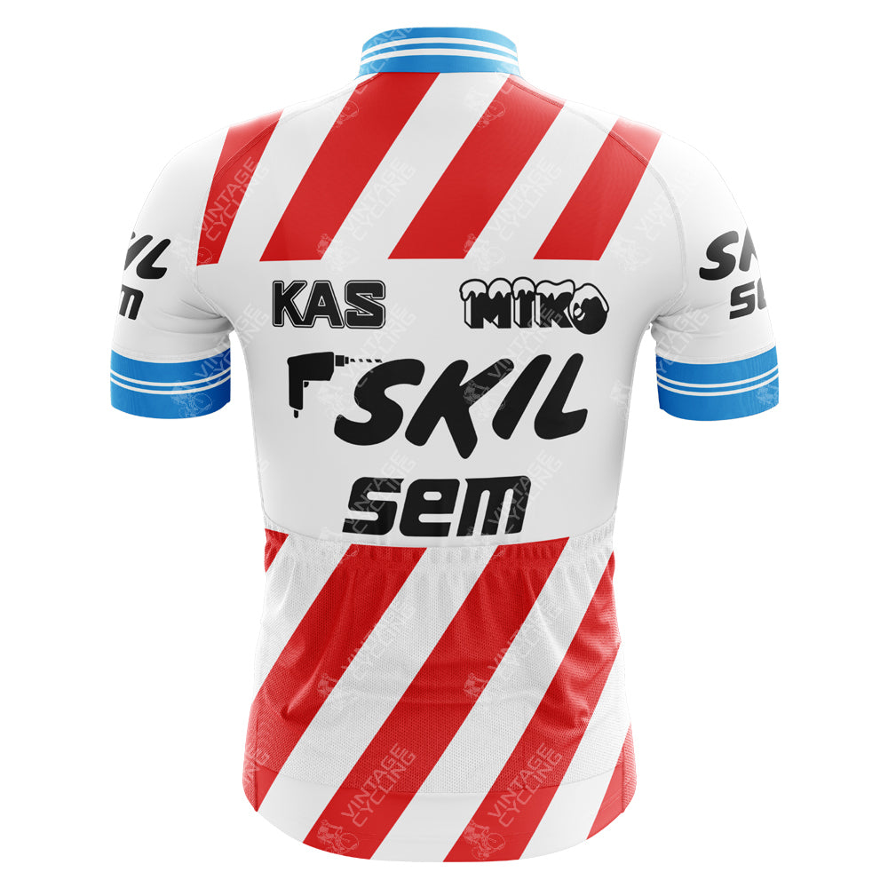The KAS Skil Sem Retro Cycling Jersey features a primarily white design with red diagonal stripes, blue cuffs, and vintage black text. Logos including SKIL, MIKO, and SEM enhance its nostalgic appeal. Made from lightweight polyester, it also has an internal silicone waist strip for a secure fit.