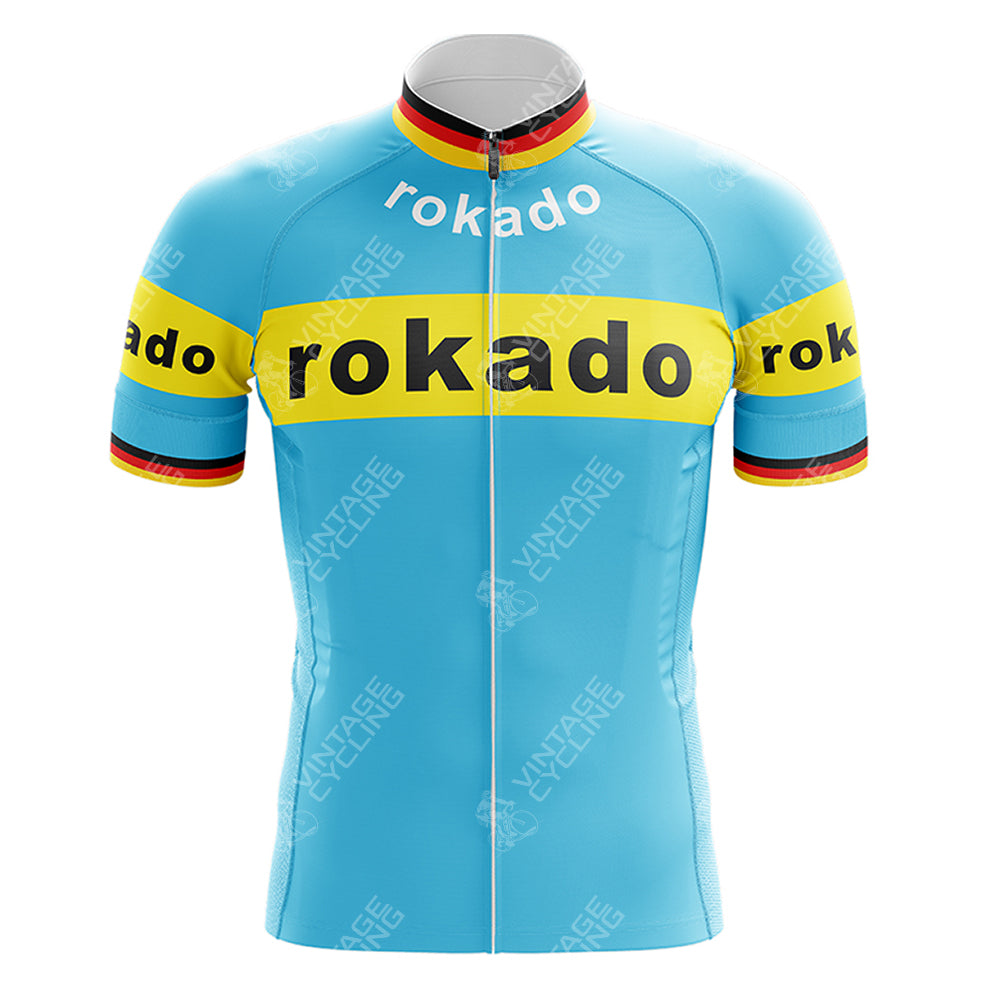 The Boule dOr Sunair Retro Short Sleeve Cycling Set showcases a light blue design with rokado in bold yellow and black on the chest and arms. Enhanced by yellow bands, narrow red and black stripes, it is completed with a white collar and front zipper for an ideal vintage look.