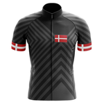The Therapy Men Short Sleeve Cycling Set is a black, moisture-wicking jersey with bold gray chevrons and Denmark’s flag on the chest and sleeves, each designed with a striking red band and white cross for standout style.