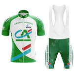 The CAFE DE COLOMBIA Retro Short Sleeve Cycling Set features a vibrant green, white, and red jersey with matching bib shorts. It showcases Crédit Agricole text and abstract patterns, merging style with performance.