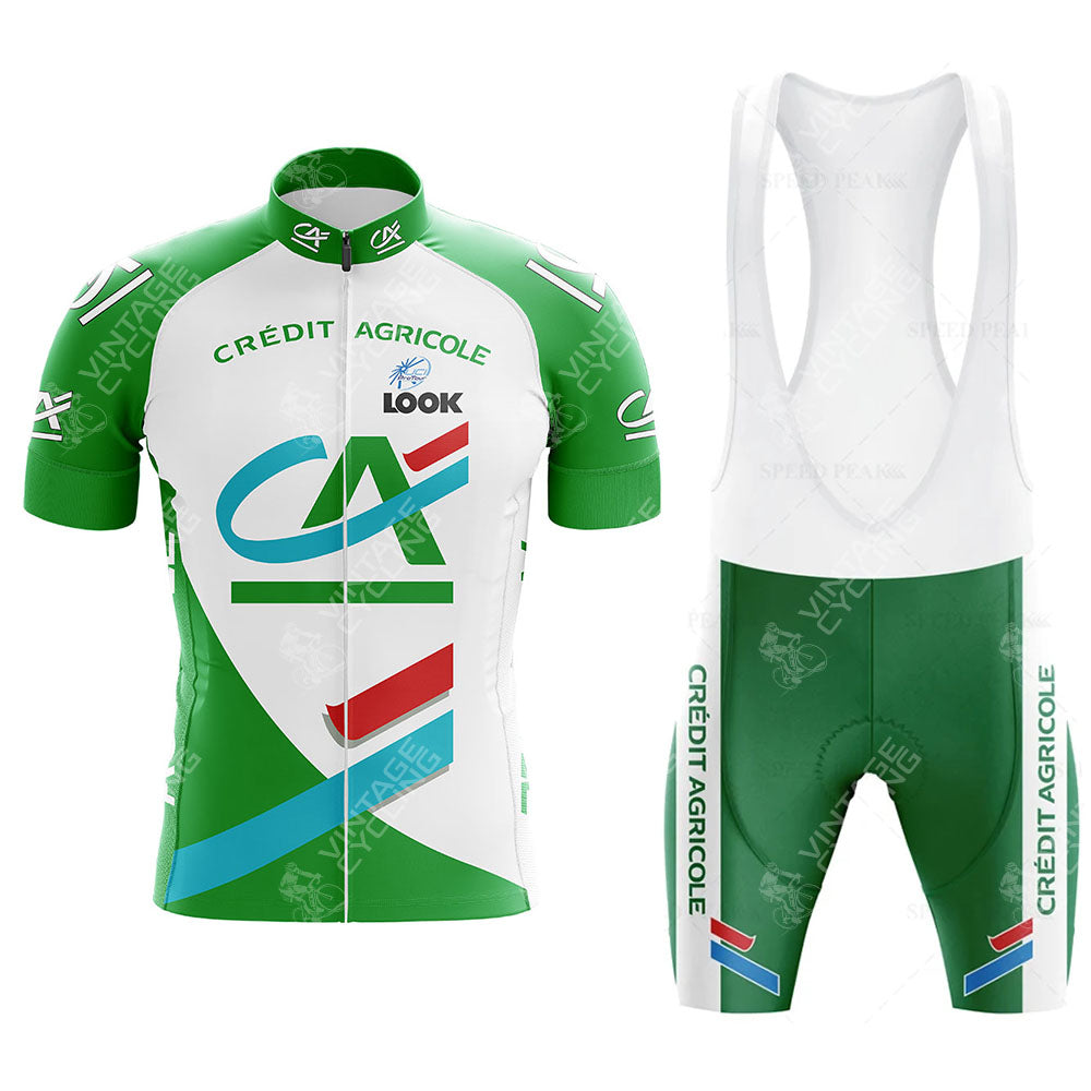 The CAFE DE COLOMBIA Retro Short Sleeve Cycling Set features a vibrant green, white, and red jersey with matching bib shorts. It showcases Crédit Agricole text and abstract patterns, merging style with performance.