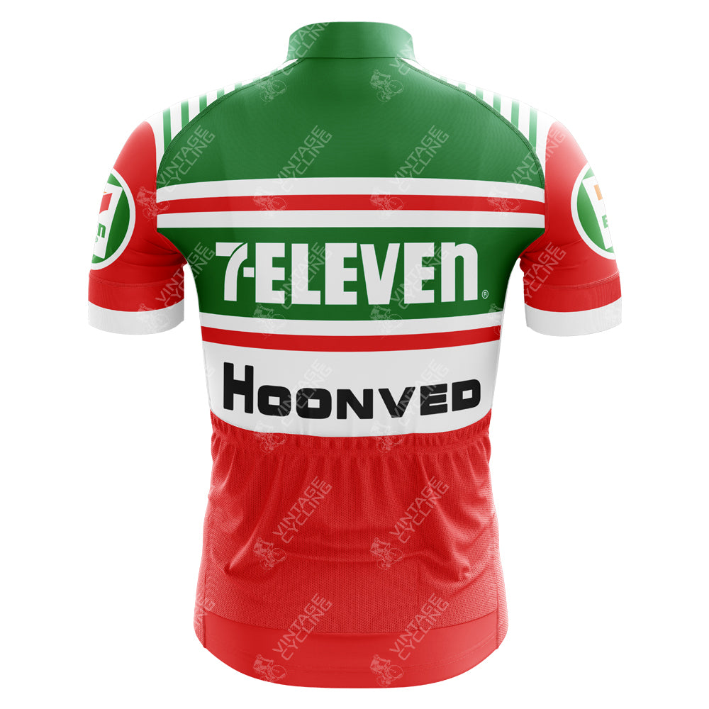 The back view of the 7-Eleven Retro Cycling Jersey showcases a red, green, and white vintage design from the 1980s, featuring 7-ELEVEN and Hoonved logos with horizontal stripes and sleeve sponsors.