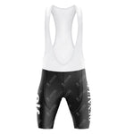 The Renault Elf Gitane Retro Cycling Jersey Set includes black and white bib shorts with shoulder straps, showcasing a subtle pattern and bold white text on the sides, capturing the iconic Tour de France style. The fitted fabric is designed for performance.