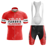 The Z Vetements Enfants Retro Short Sleeve Cycling Set features a red and white kit, with the jersey displaying Velda and Flandria amidst black and white stripes. The bib shorts offer a sleek black design accented by bold red details.