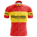The Reynolds-Papel Alumino Retro Cycling Jersey is a lightweight polyester jersey in vibrant red with yellow horizontal stripes on the chest and sleeves. It features Reynolds-Papel Alumino in bold black letters across the front for a classic, vintage look.