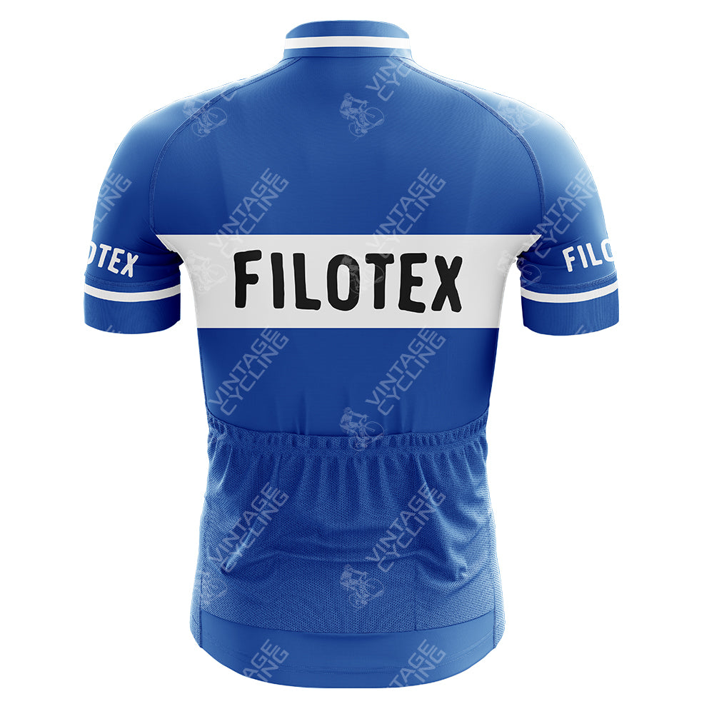 The G.B.C. - LIBERTAS Retro Cycling Jersey, in blue, showcases a white FILOTEX band on its back. Made from lightweight polyester, it includes short sleeves, elastic cuffs, and rear pockets with a faded Vintage Cycling watermark adorning this performance jersey.