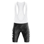 The Renault Elf Gitane Retro Cycling Jersey Set includes black and white bib shorts with shoulder straps, showcasing a subtle pattern and bold white text on the sides, capturing the iconic Tour de France style. The fitted fabric is designed for performance.