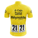 A retro yellow Del Tongo-MG Maglificio Cycling Set jersey with bold black Caja Postal and Reynolds Aluminio logos on the back, plus two race number tags—both marked 21 Caja Postal—pinned to the lower back.