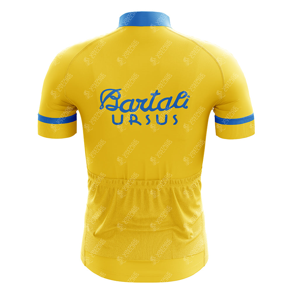 The Bartali Ursus Retro Cycling Jersey features a vibrant yellow design with blue cuffs and collar. It showcases a blue logo and Bartali URSUS text on the back, honoring Gino Bartali. Stitch detailing adds charm, and a bottom pocket offers practicality.