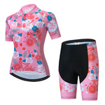 The Womens Pink Floral Cycling Jersey Set includes a vibrant floral-themed jersey with short sleeves and a front zipper, paired with shorts featuring black padding and matching pink leg accents.