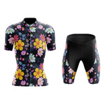 The Womens Floral Big Yellow Cycling Jersey Set features a lightweight polyester, black short-sleeve jersey and shorts adorned with vibrant yellow, pink, and blue flowers. It includes a gel seat pad for extra comfort on every ride.