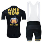 The Bike Now Beer Later Cycling Jersey Set is a black outfit with yellow accents, featuring a beer-themed jersey with Bike Now and Beer Later under two clinking mugs. It includes bib shorts with a gel seat pad for comfort, complemented by white straps.