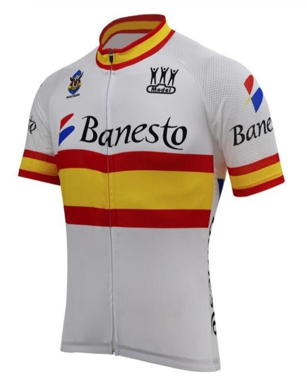 The Banesto Spanish Flag Retro Cycling Jersey features a white, red, and yellow design inspired by the Spanish flag with Banesto printed on the front. Celebrating Miguel Indurains legacy, it has a high collar, short sleeves, and logos with color accents on the collar and sleeve cuffs.