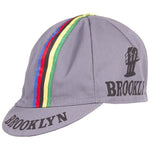 The Brooklyn Retro Cycling Cap is gray with vibrant multicolored stripes (green, yellow, red, blue) on top. It features Brooklyn and a stylized bridge in black on the side and brim, capturing the classic retro vibe of Brooklyn Chewing Gum.