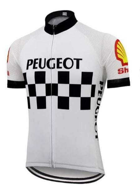 The Classic 1960s Peugeot Shell Retro Cycling Jersey Set features a checkered pattern with black Peugeot text, echoing Eddy Merckxs era. It includes logos on the sleeves: a red and yellow seashell and Shimano in red. It has a black collar, zipper front, and mesh panels for breathability.