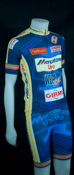 The mannequin sports the Mercatone Uno Wega Retro Cycling Jersey Set, featuring a blue design with yellow and red accents and sponsor logos. Its vibrant style resembles Marco Pantanis team kit, striking vividly against the dark background.