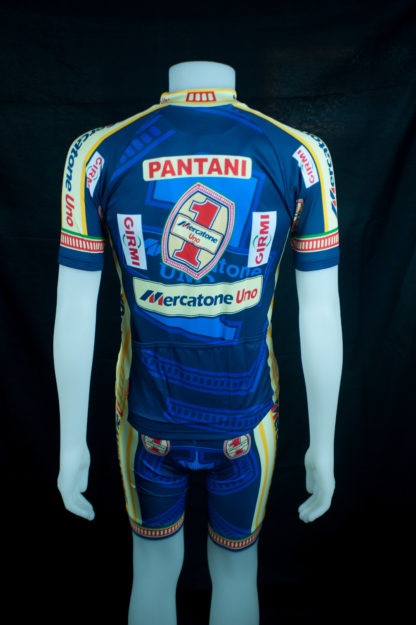 A vibrant retro cycling jersey shown from the back features blue, yellow, and red colors. With Pantani and sponsor logos Girmi and Mercatone Uno, this Mercatone Uno Wega Retro Cycling Jersey Set honors Marco Pantanis legendary rides.