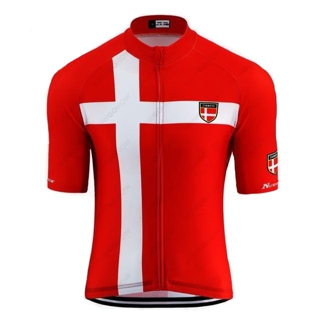 The Denmark Cycling Jersey is made from lightweight polyester, featuring a bold red design with a large white cross. It includes an emblem on the left chest and sleeve, short sleeves, and a reflective zipped back pocket for extra functionality.