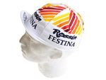 The Festina Watches Retro Cycling Cap on a mannequin head showcases a white cap with a retro geometric pattern in red, orange, and yellow. It features Rossin and Festina printed in black, exuding timeless elegance reminiscent of Festina Watches heritage.