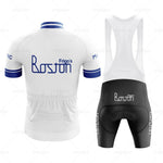 The Frigos Boston Retro Cycling Jersey Set includes a white and blue jersey with the Frigos Boston logo, featuring a blue collar and cuffs for comfort. It comes with matching black bib shorts displaying the same logo on the side.