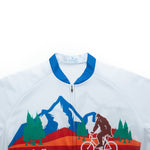 The Big Foot Sasquatch Cycling Jersey Set features a silhouette of Bigfoot on a bicycle amid blue mountains, green trees, and an orange landscape. Made from lightweight polyester, it has a blue collar with the rest predominantly white.