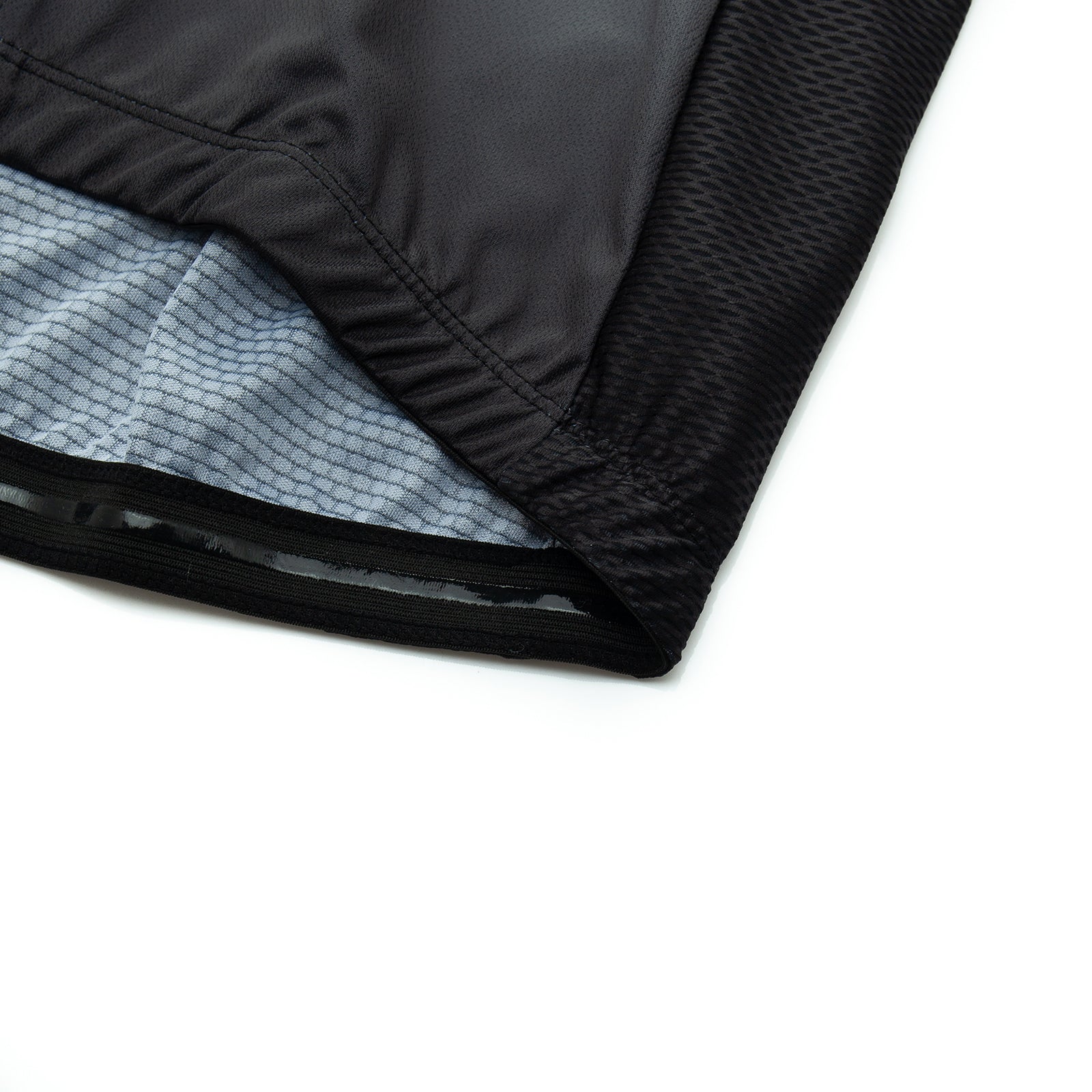 Close-up of a black fabric from the US Army Veteran Cycling Jersey Set, showing the edge and inner gray lining with a grid pattern. The athletic wear material displays texture and stitching details on a white background.