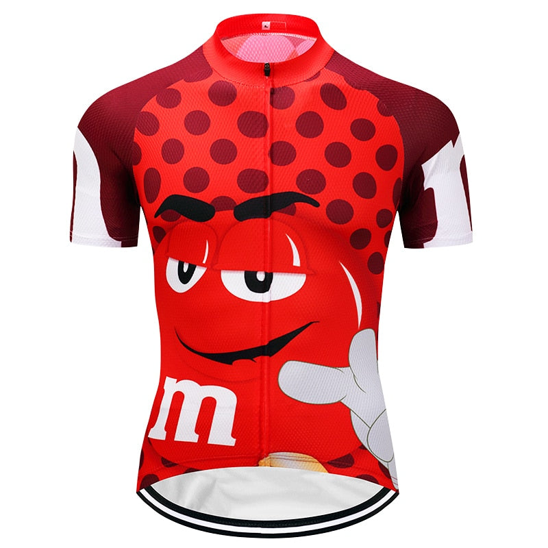 Try the M&Ms Red Cycling Jersey, designed from lightweight polyester for top performance. This red jersey features a cartoon candy character with a white m giving a thumbs up, red polka dots on the chest, and bold red and white sleeves.