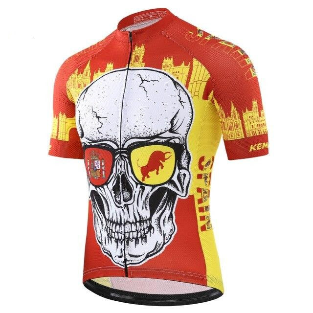 The Spain Skull Cycling Jersey is made of lightweight polyester and showcases a skull with sunglasses, displaying a coat of arms on the left lens and a bull on the right. Adorned with Spanish architectural motifs in red and yellow, it features Spain on the side for added pride.