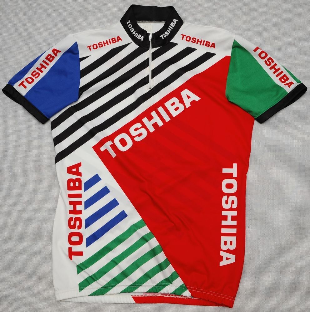 Discover the Toshiba 1990 Retro Cycling Jersey, inspired by Laurent Jalaberts 1990 Vuelta Espana style. It features a bold geometric design in vibrant red, blue, green, and black and prominently displays TOSHIBA across its fabric.