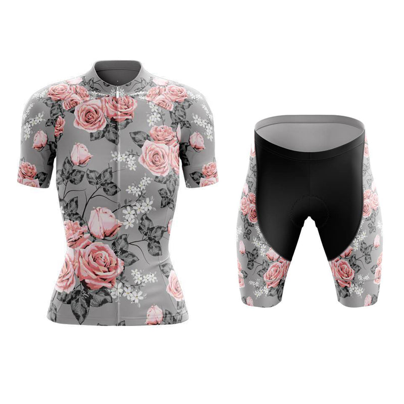 Explore the Womens Floral Grey Pink Cycling Jersey Set, made from lightweight polyester. This gray set has a pink and white rose pattern with black leaves. The jersey includes short sleeves and a full zipper, while the shorts feature a gel seat pad and floral accents near the top.