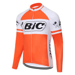 The BIC Orange Long Sleeve Retro Cycling Jersey features an orange and white design with a full-length zipper and Bic logos on the chest, sleeves, and sides. It offers a classic look with the option of added fleece for comfort.