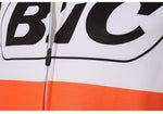 Close-up of a BIC Orange Long Sleeve Retro Cycling Jersey, featuring bold black BIC lettering on a white background with an orange band below. A visible vertical zipper runs through the center.